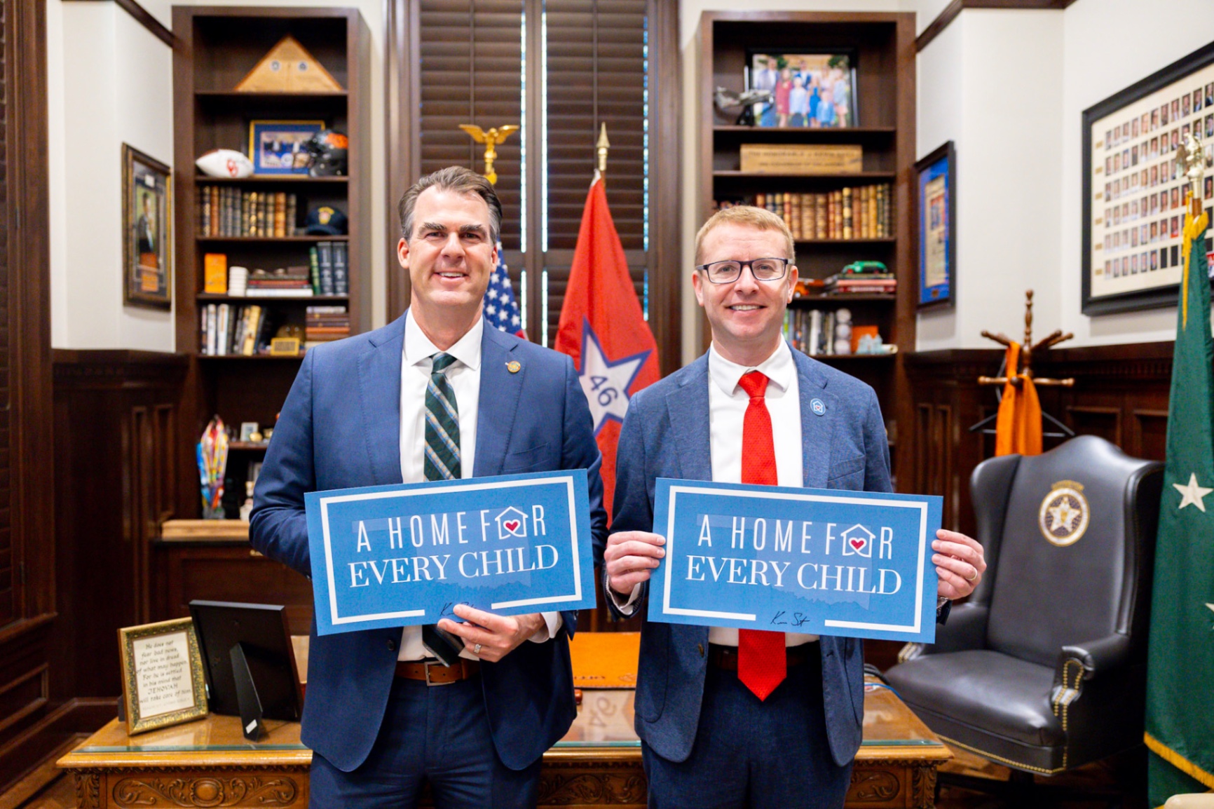 Governor Kevin Stitt and ACF Assistant Secretary Alex Adams holding 'A Home For Every Child' signage in the Governor's office.