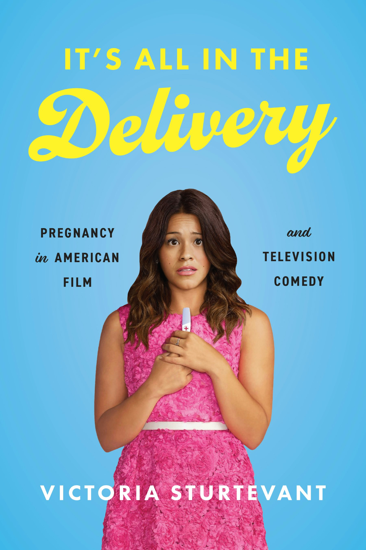 Book cover of 'It's All in the Delivery: Pregnancy in American Film and Television Comedy' by Victoria Sturtevant, featuring yellow script typography on a blue background with a portrait of a woman in a pink dress holding a pregnancy test.